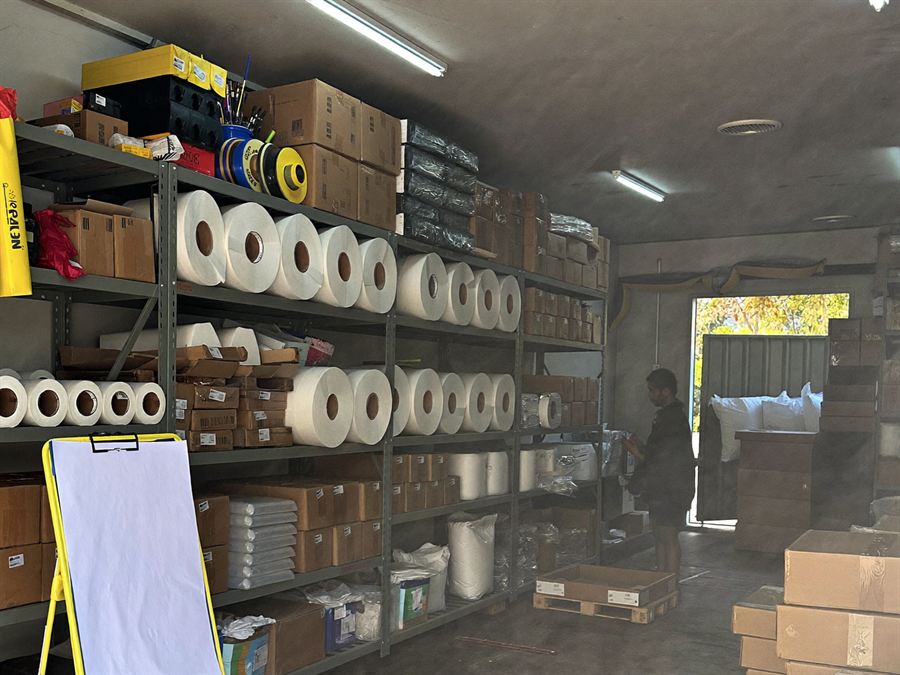 Estanterías de bodega con rollos de material, cajas y empaque organizados
